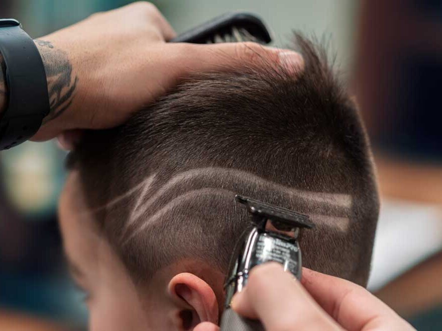 Barber creating a hair line design.